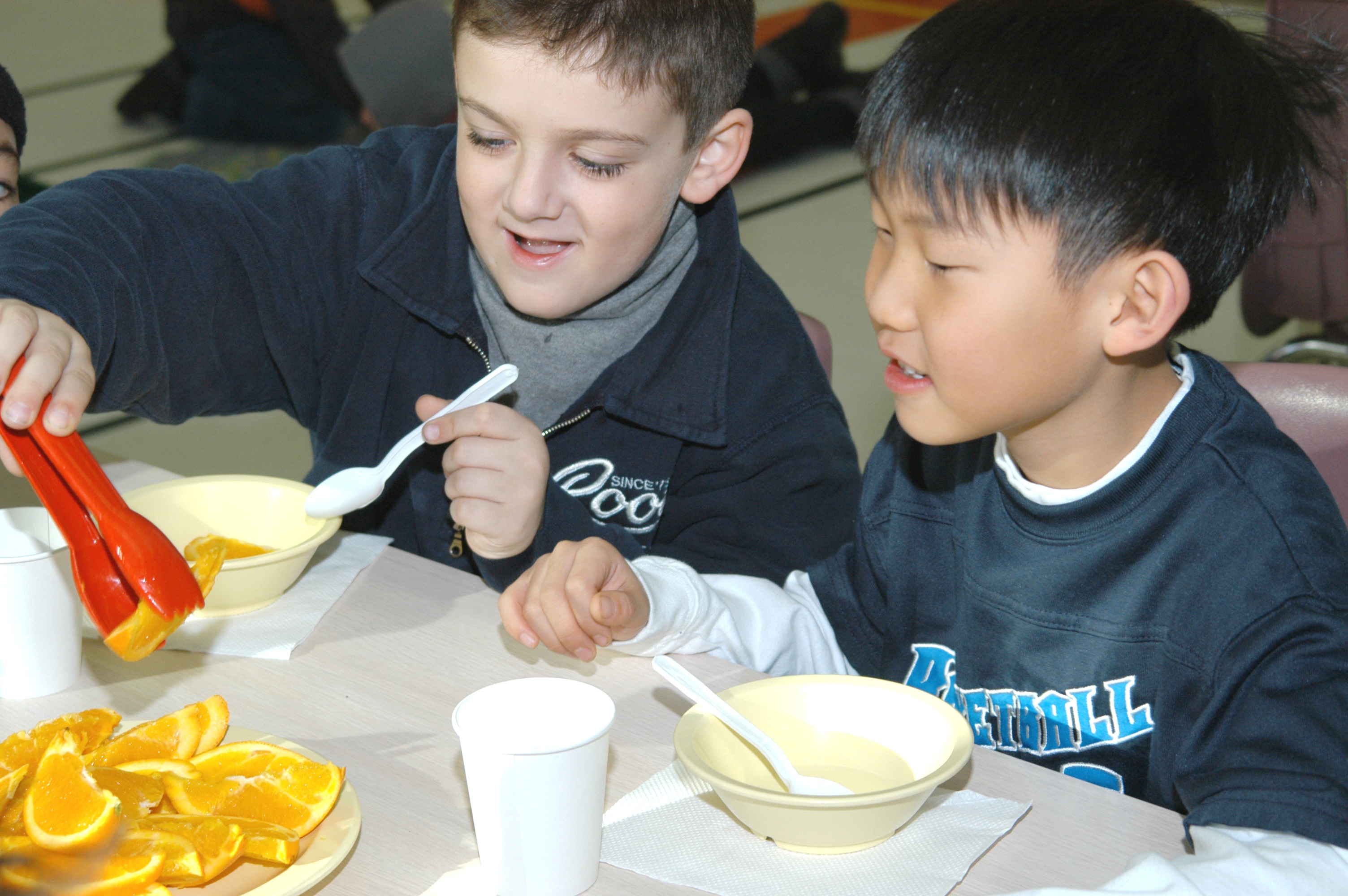 Two boys share a snack of sliced oranges at a PLASP program