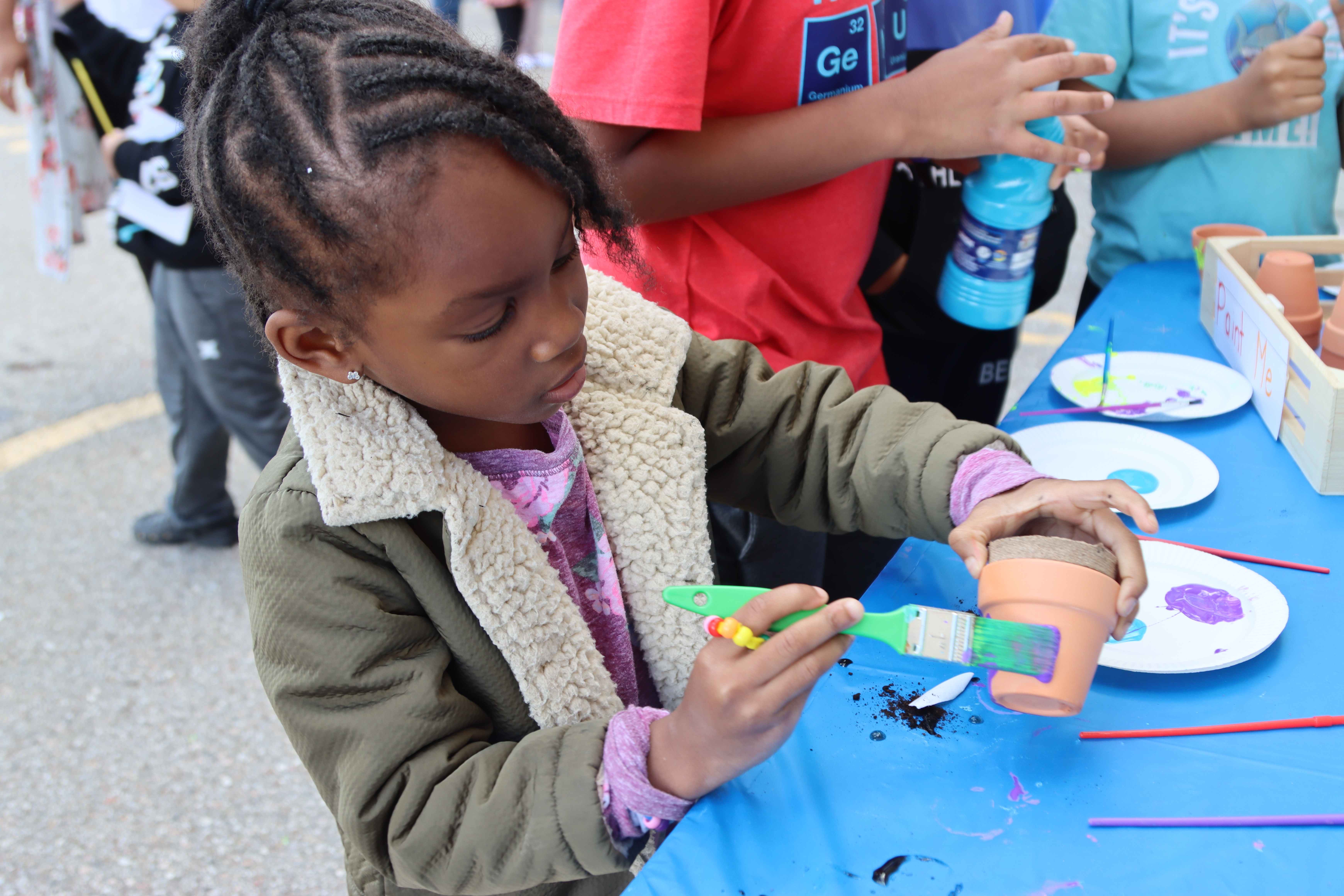 A girl in a PLASP kindergarten program paints a flower pot