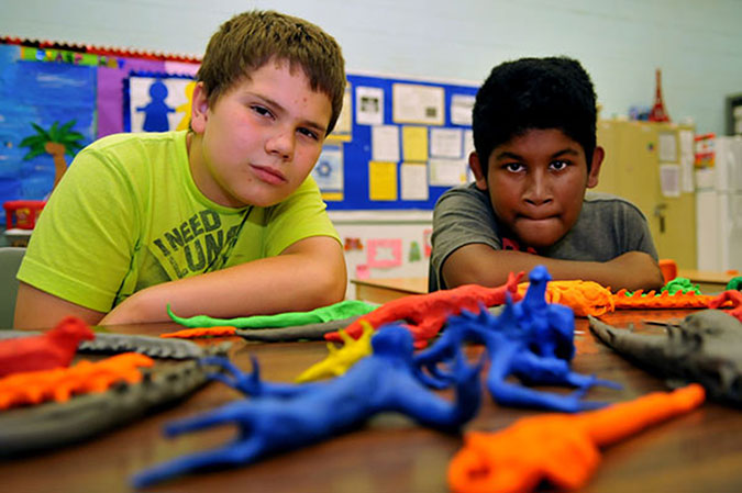 Two children with a bunch of Plasticine creations