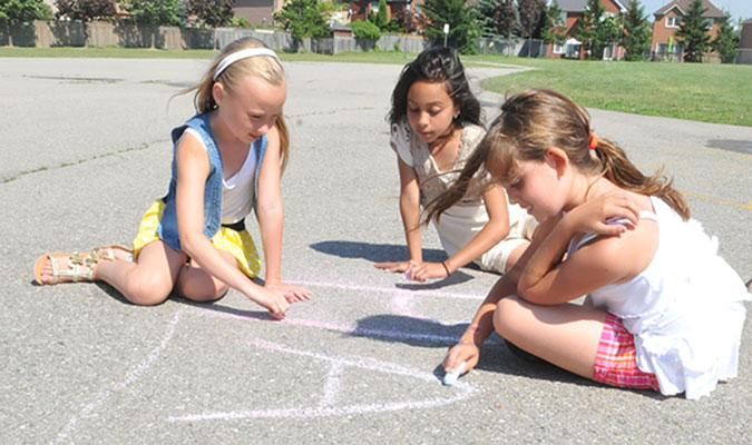 Three girls drawing on the ground with chalk