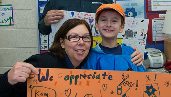 A child and a custodian holding up a handmade card