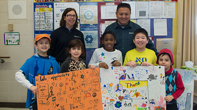A group of PLASP children present two school custodians with a handmade card