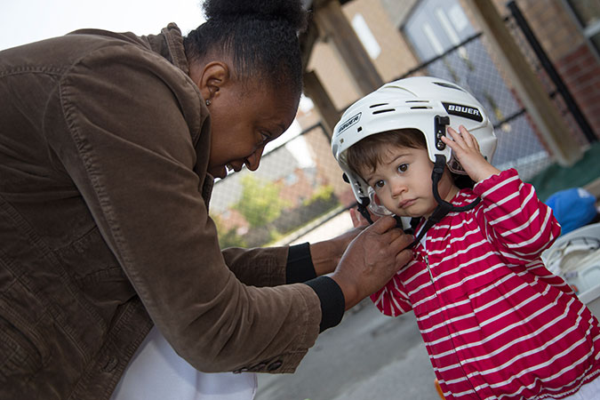 A PLASP staff helps a child put on a helmet