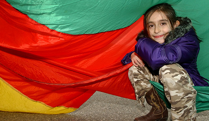 A child underneath a colourful parachute