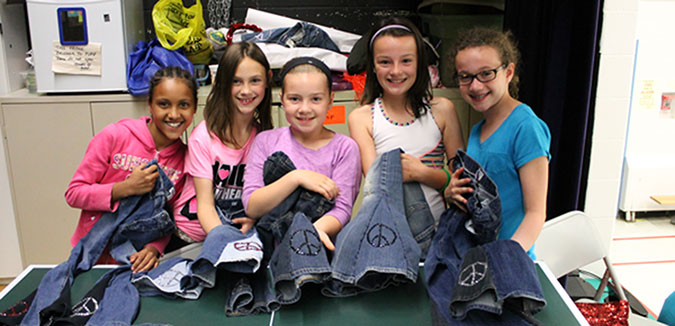 Five girls with a pile of bell bottom jeans