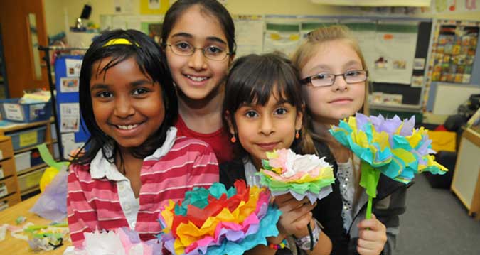 Four children hold bouquets of tissue paper flowers