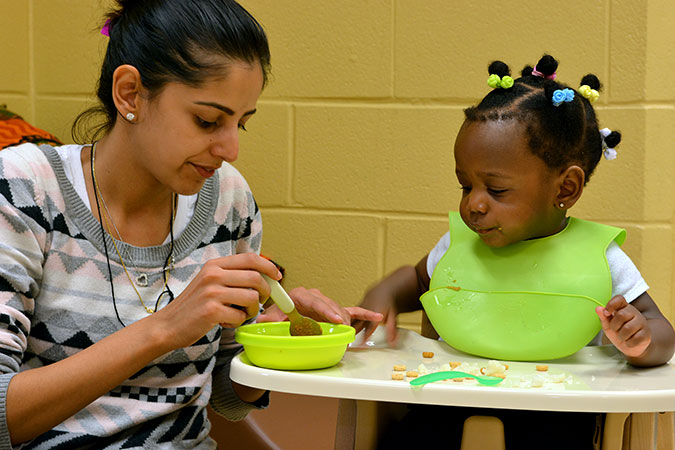 A PLASP staff member with a child in a high chair