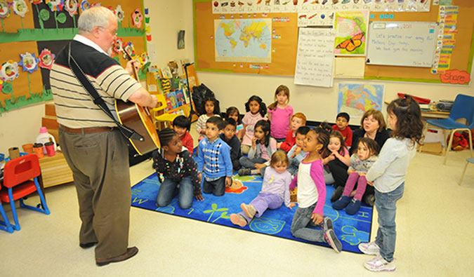 Jim the Music Man plays the guitar to a group of children