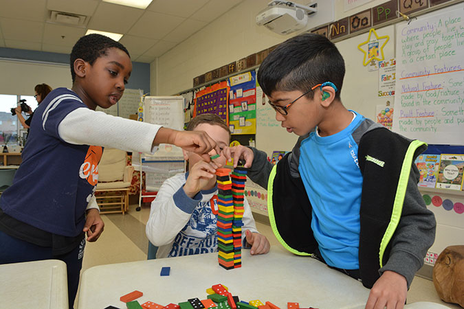 Three children play with dominoes