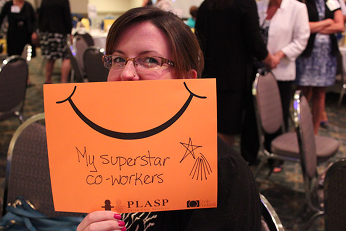 A PLASP staff holds up an orange card with a smiley on it