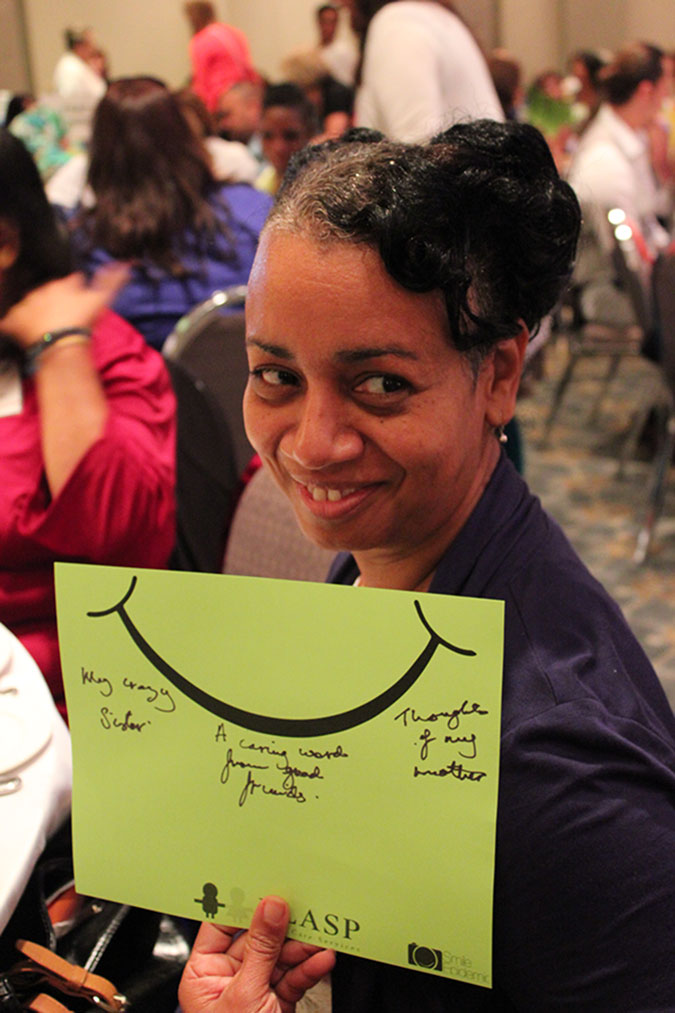 A PLASP staff holds up a yellow card with a smiley on it