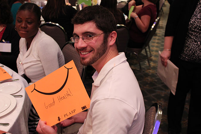 A PLASP staff member holds up an orange card with a smiley on it