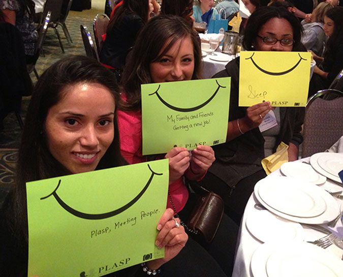 Three PLASP staff hold up cards with smileys on them