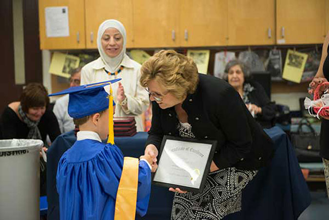 Vice President Sandy Edmonds presents a child with a "diploma"