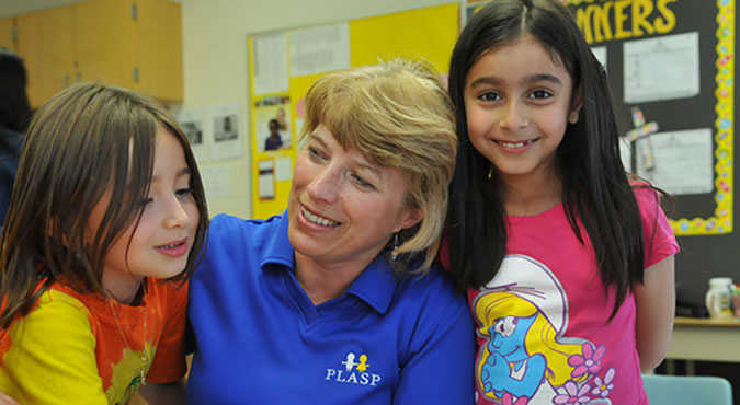 A PLASP staff member shares a hug with two girls