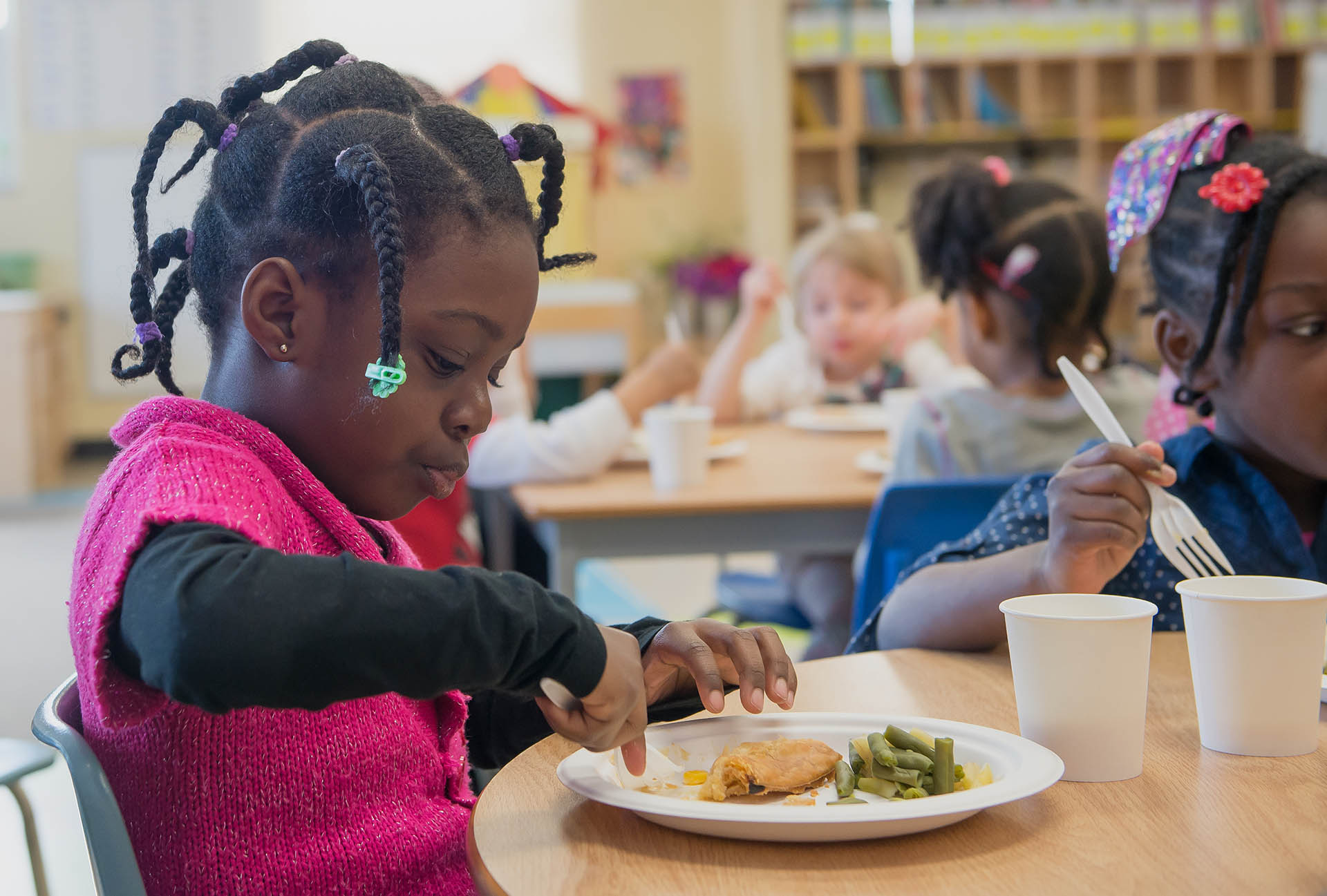 A little girl in the Kindergarten program enjoys a healthy snack of green beans and a wrap