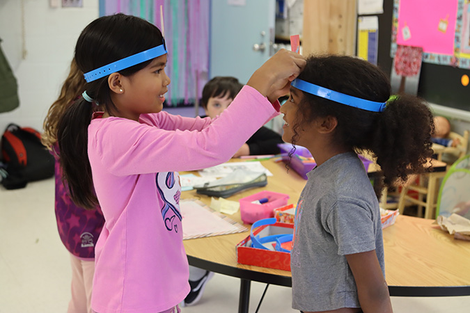 Two children make headbands in a PLASP program