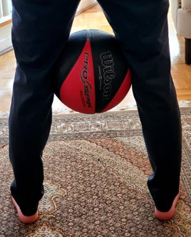 Child holding basketball between their knees