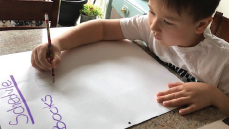 Child writing a schedule on a large sheet of paper